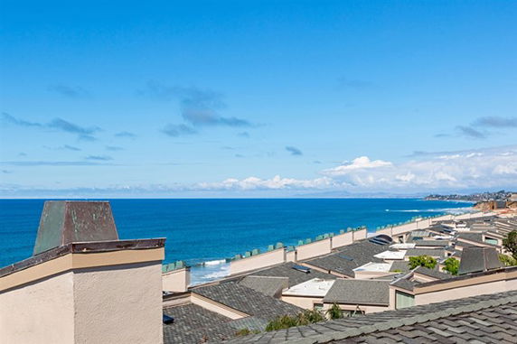 Panoramic view from a rooftop overlooking the ocean and nearby buildings.