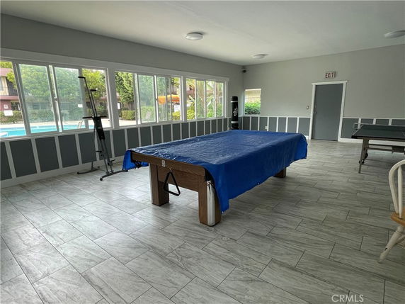 Indoor recreation room with a pool table and large windows.
