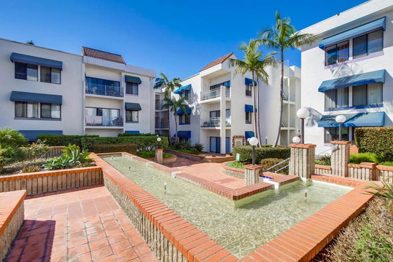Front view of a multi-story building with balconies and blue awnings.