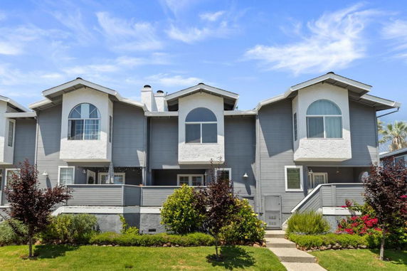 Front view of a multi-story house with gray siding and arched windows.
