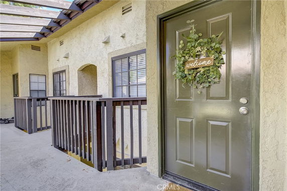 Front view of a building with a green door adorned with a welcome wreath and adjacent windows.