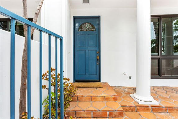Front entry view of a house with a blue door and terracotta steps.