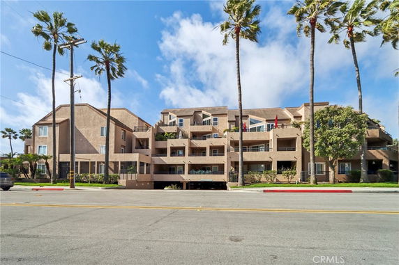 Front view of a multi-story residential building with balconies and a flat roof.