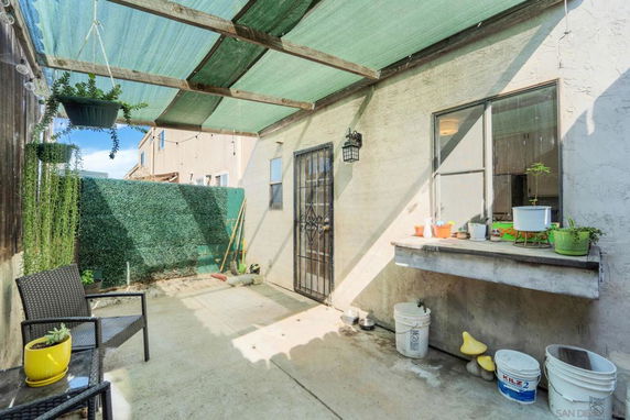 Outdoor patio area with a shaded canopy and potted plants.