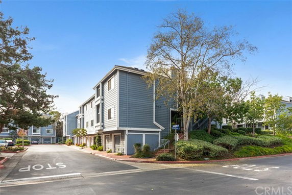 Front view of a multi-story residential building with gray siding and white trim.
