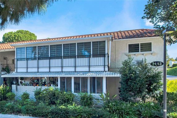 Front view of a two-story house with a tiled roof and a balcony.