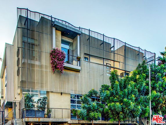 Front view of a modern multi-story building with metal mesh facade.