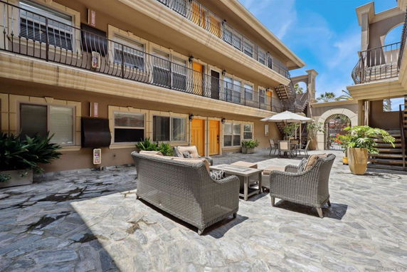 Outdoor courtyard with wicker furniture and multiple balconies in a multi-level building.
