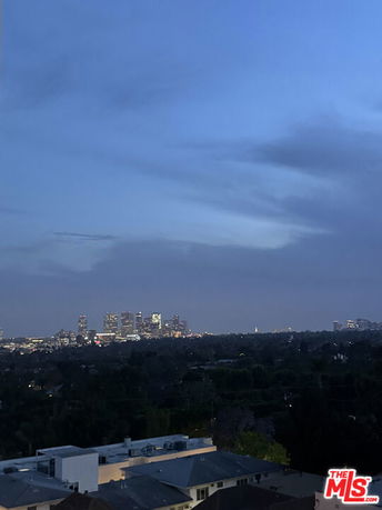 Panoramic view of a city skyline at dusk, with distant high-rise buildings and an expansive sky.