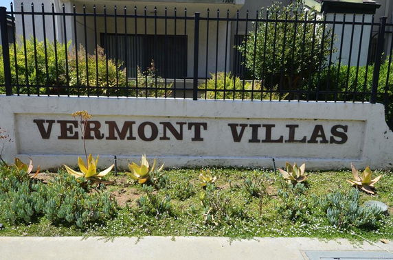 Front view of the entrance to Vermont Villas with a sign and surrounding plants.
