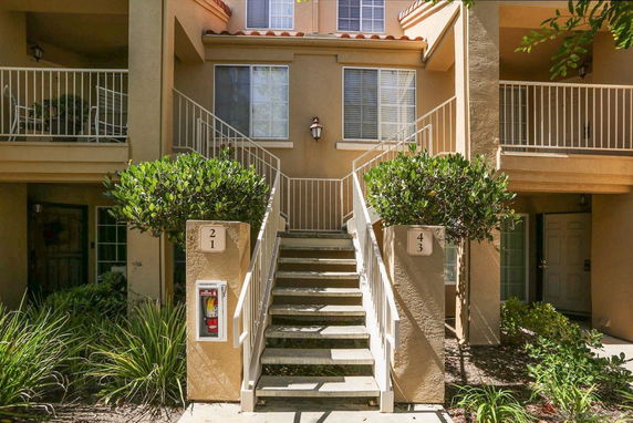 Front view of a multi-story residential building with stairs leading to upper levels.