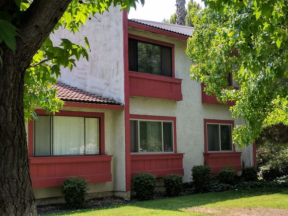 Front view of a two-story house with red trim and multiple windows.