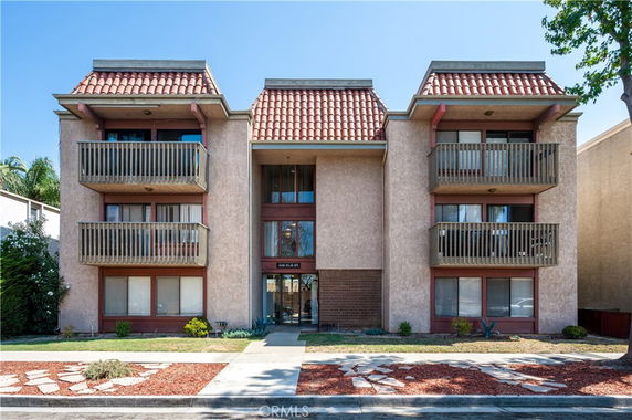 Front view of a multi-story building with balconies and tiled roof sections.