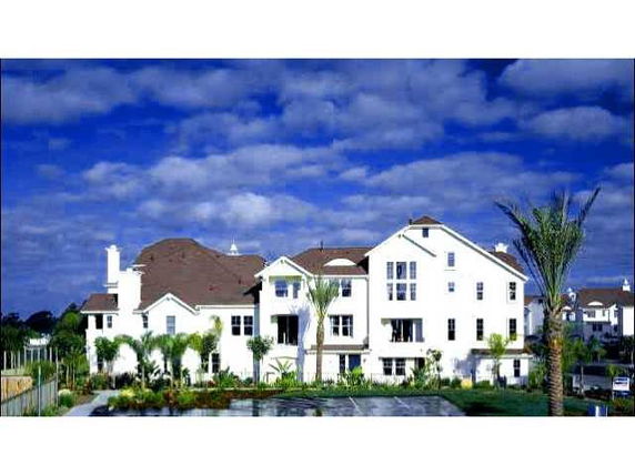 Front view of a multi-story house with white exterior and brown roof.