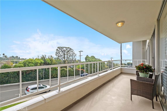 Balcony view overlooking a road and foliage with a partial view of the surroundings.