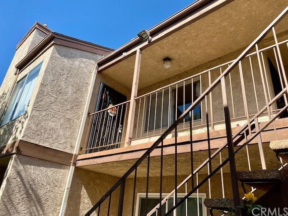 Front view of a multi-story building with external staircase and balcony.