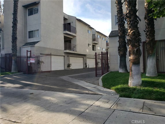 Front view of a multi-story apartment building with garages on the ground level.