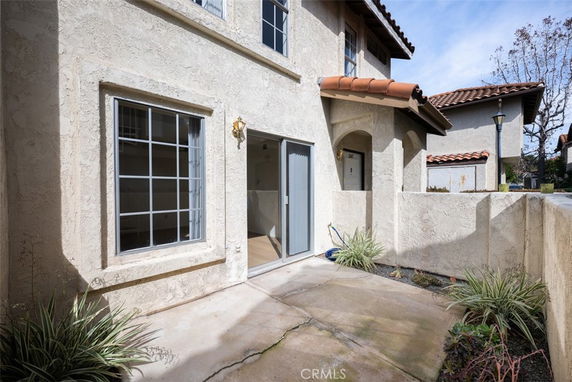 Front view of a two-story house with textured walls and a small enclosed patio area.