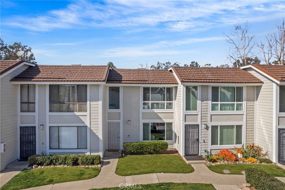 Front view of a two-story townhouse with brown roof shingles and white siding.