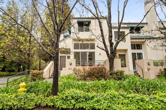 Front view of a multi-story residential building with large windows and greenery.