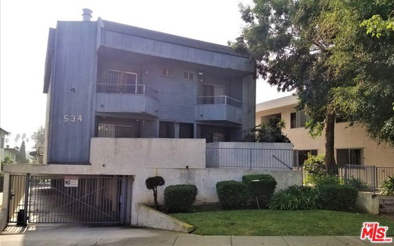 Front view of a multi-story building with balconies and a gated entrance.