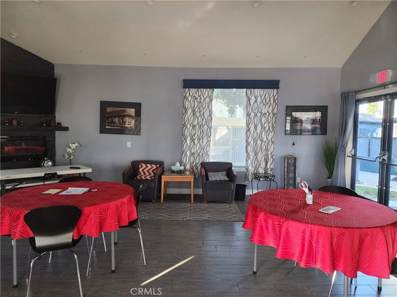 Interior room with tables covered in red cloth, chairs, and a wall-mounted TV.