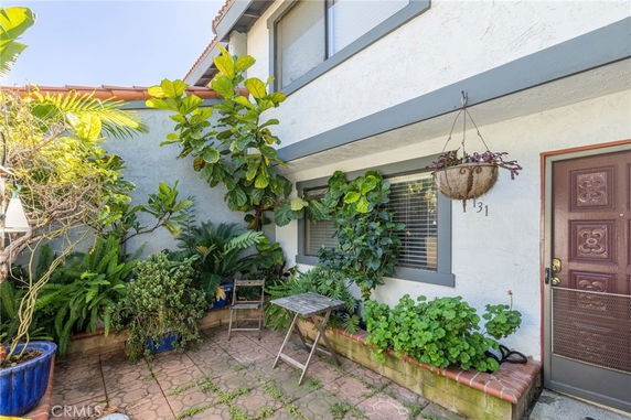 Front view of a two-story house with plants in the courtyard.