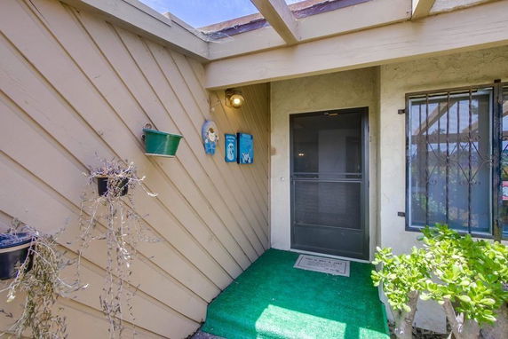 Front view of a house entrance with decorative plants and wall art.