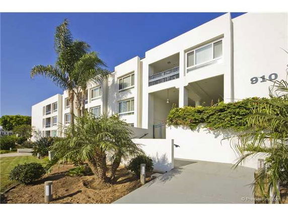 Front view of a multi-story white building with balconies and large windows.