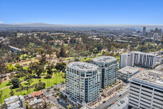 Aerial view of urban landscape with tall buildings and a park in the background.