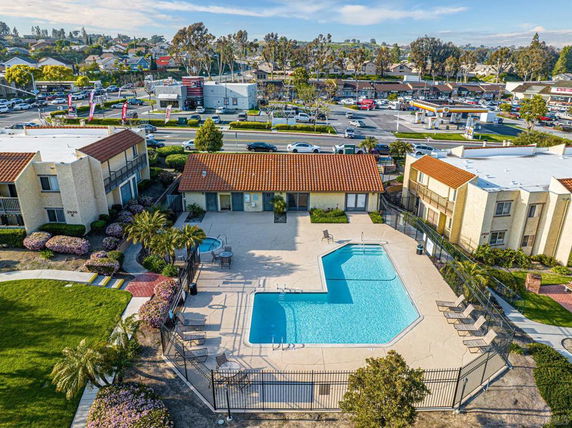 Aerial view of a residential complex with a central swimming pool and surrounding buildings.