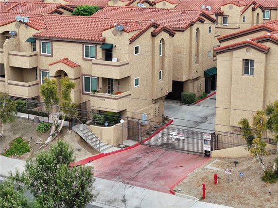 Front view of a multi-story apartment building with balconies and gated entrance.