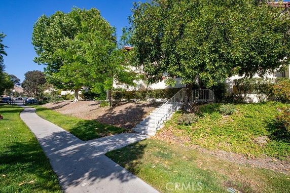 Front view of a building with stairs leading to the entrance, surrounded by trees and landscaping.