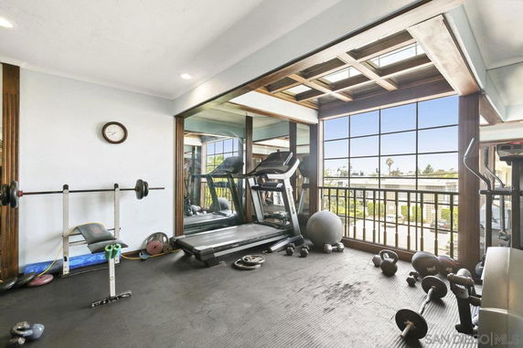 Indoor fitness area with exercise equipment including a treadmill and weights.