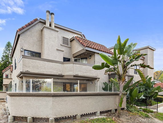 Front view of a multi-story house with a balcony and a sloped roof.
