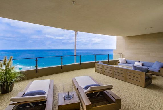 Spacious balcony with ocean view and outdoor seating.