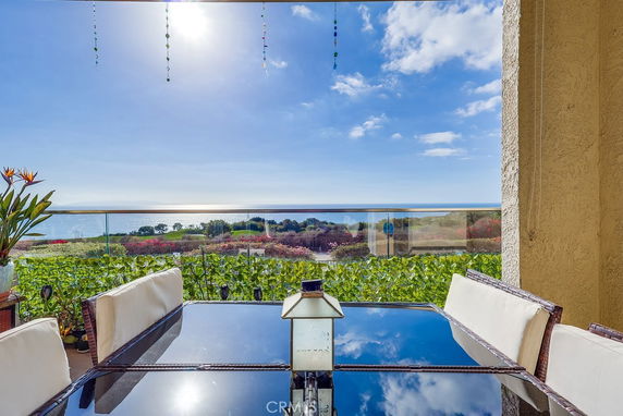 Panoramic view from a patio overlooking the ocean and surrounding landscape.