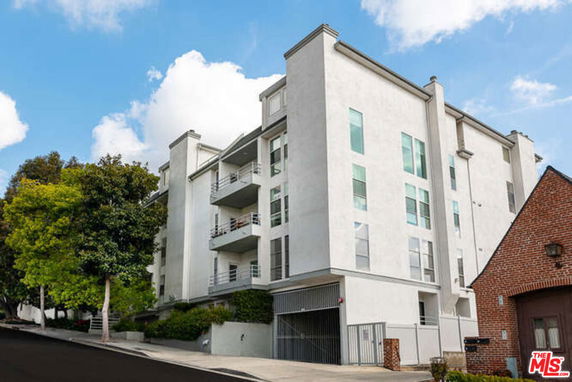 Front view of a multi-story building with balconies and a gated entrance.