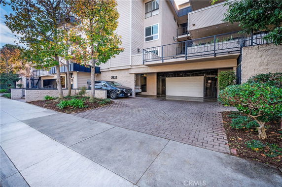 Front view of a multi-story apartment building with a parking area and garage.