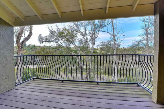 Balcony view overlooking a landscape with trees and distant hills.