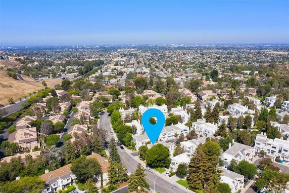 Wide view of a residential area with multiple houses and greenery seen from above.