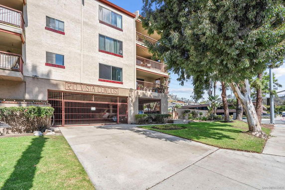 Front view of a multi-story condominium building with balconies and gated entrance.