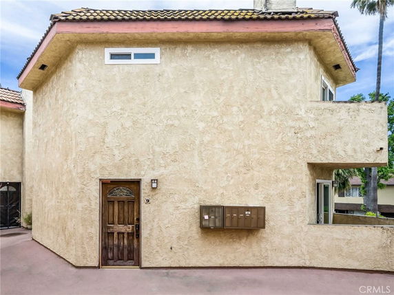 Front view of a beige stucco house with a small window and wooden door.
