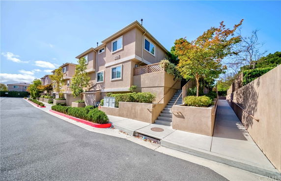 Front view of a multi-story residential building with stairs leading up to the entrance.