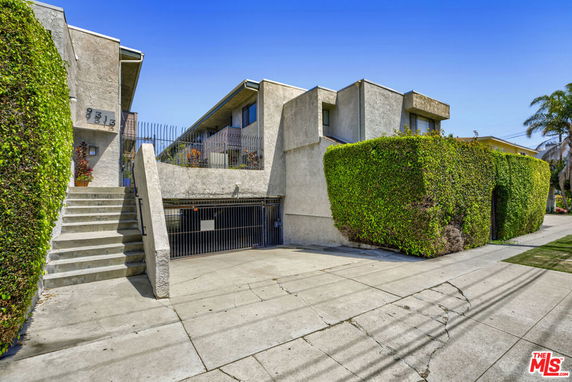 Front view of a multi-story building with a staircase and gated entrance.