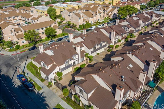 Aerial view of residential buildings with brown roofs and chimneys in a neighborhood setting.