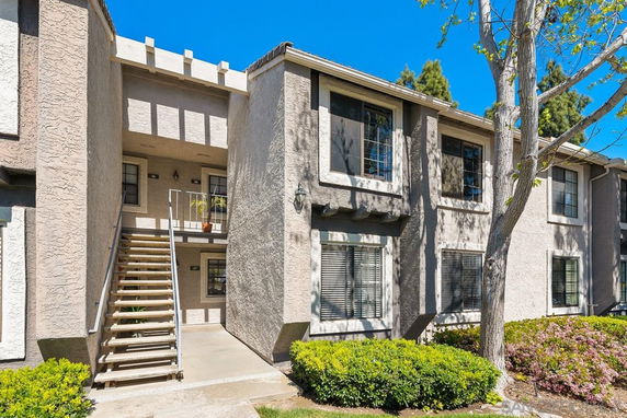 Front view of a two-story apartment building with exterior staircase and multiple windows.