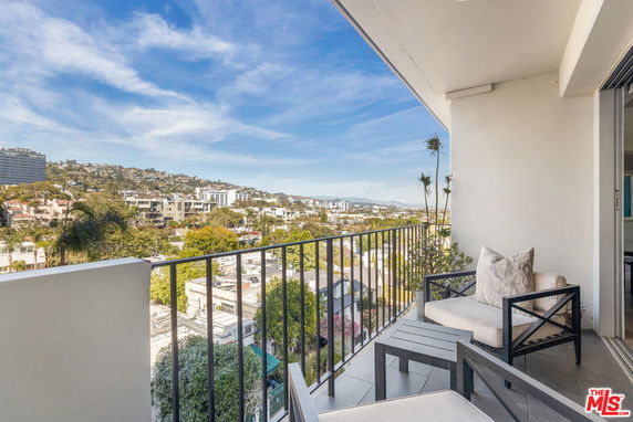 Panoramic view from a balcony overlooking a cityscape with hills in the background