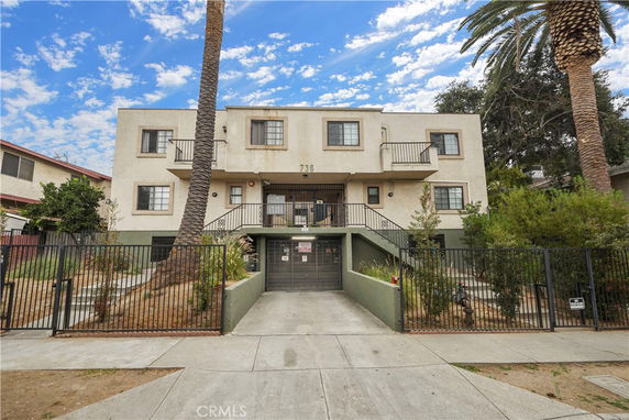 Front view of a multi-story residential building with balconies and a gated entrance.