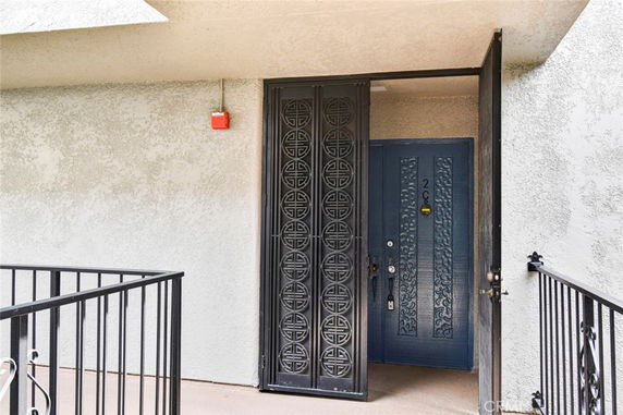 Entrance to a unit with decorative metal door and blue main door.